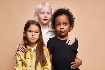 adorable kids of diverse nationalities and skin colors stand together posing at camera, group of...