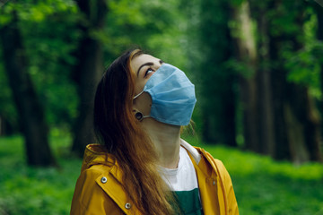 female portrait in mask wish to breathe by clean air and looking on nature, actual pollution and...