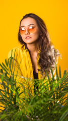 a girl on a yellow background with contempt looks sideways, in yellow glasses and yellow clothes, on a yellow background