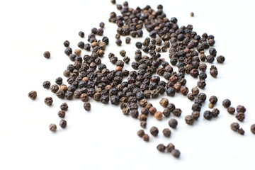 Black peppercorns in bowls on white wooden background