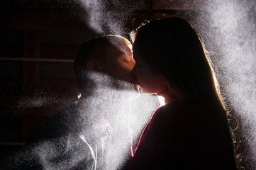  loving couple kisses under the drops of illuminated water