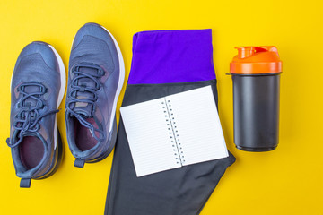 Sports layout. Fitness accessories sneakers, clothes, headphones and watches on a yellow background. Go in for sports and fitness at home