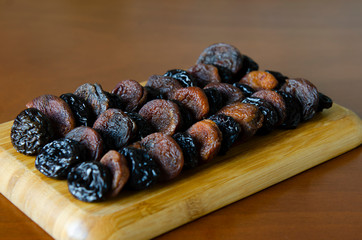 dried apricots and prunes on a wooden plate, dried fruits,