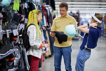 Fototapeta premium young caucasian customers came in sportswear store to make purchase, handsome guy and woman get involved in various sport, huge. large assortment of goods around