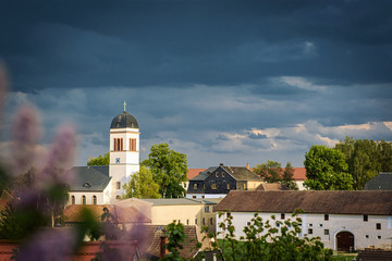 Kirche, Kirchturm, Dorf, vor Gewitterhimmel, mit Flieder, unscharf im Vordergrund, dramatisch,...