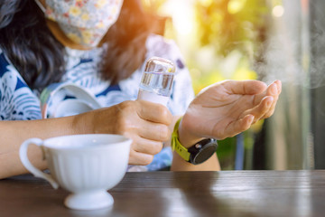 Woman using alcohol nano mist sprayer antiseptic cleaning on her hands protection during...