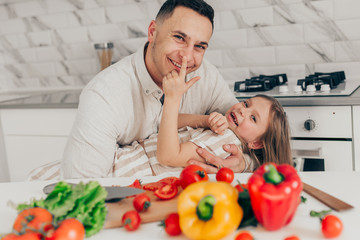Father's day. Dad and his child daughter are cooking and having fun together in the kitchen. Family holiday.