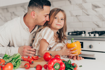 Father's day. Dad and his child daughter are cooking and having fun together in the kitchen. Family holiday.