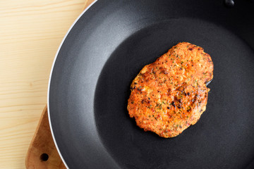 Chicken fillet fried in a pan. Chop is prepared with herbs and spices. Fresh hot roasted meat. Closeup black background.