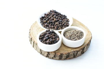 Fototapeta na wymiar Black peppercorns in bowls on white wooden background