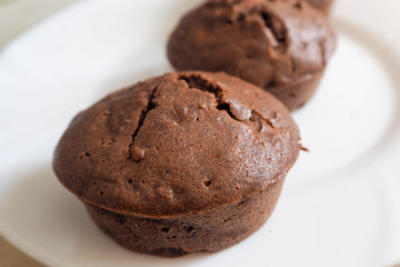 macro gluten-free chocolate muffins made from rice and corn flour on a white plate. gluten-free diet. sweets prepared at home