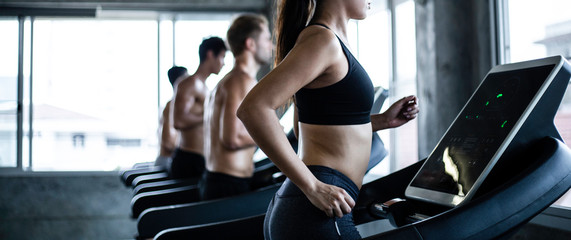 Group of Caucasian athletic people running workout on treadmill. side view of muscular men and woman do fitness exercise training at gym. healthy and lifestyle concept. banner with copy space