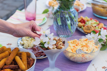 on the table are snacks and a woman's hand decorates the dish with flowers