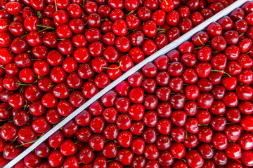 Ripe sweet cherries in a box in the market. A lot of red berries. Background. Space for text. Top view.