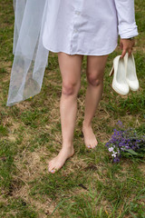 barefoot woman in a white shirt holding white shoes