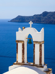 Fototapeta na wymiar White church bells against blue sea and sky background. Oia Santorini, Greece.