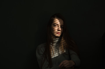 portrait of a girl against a dark background, the light from the window falls on the girl’s face, I create shadow stripes on the blinds