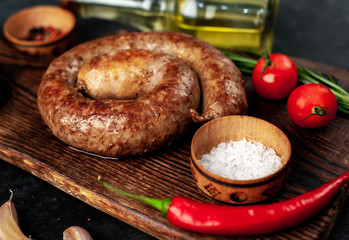 grilled spiral sausage with spices on a cutting board on a stone background