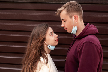 Portrait of young couple standing outdoors with covering face mask against COVID-19