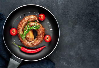 grilled spiral sausage with spices in a pan on a stone background with copy space for your text