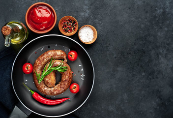 grilled spiral sausage with spices in a pan on a stone background with copy space for your text
