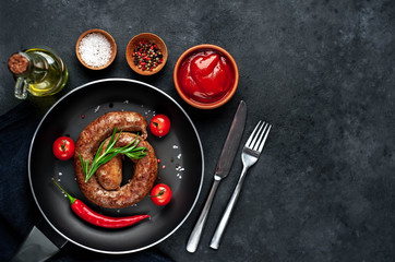 grilled spiral sausage with spices in a pan on a stone background with copy space for your text