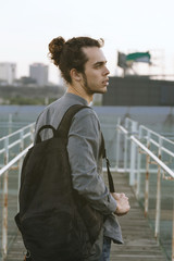 Man wearing black backpack turning around. Walking and thinking. Background of cityscapes. Urban lifestyle travel concept