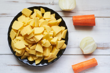 peeled sliced raw potatoes on a wooden board. Preparing vegetables for cooking.