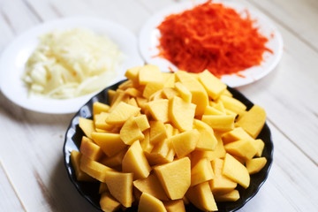raw carrots grated, chopped onions, potatoes. Preparing to cook baked potatoes with vegetables.