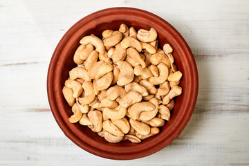 Cashew nuts in a bowl on a wooden background.