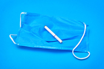 The concept of health and cigarettes. Cigarette in a medical mask on a blue background.