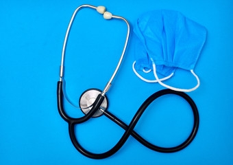 Phonendoscope and medical mask on a blue background. Medicine concept.