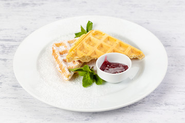Belgium waffles in powdered sugar with raspberry jam