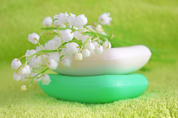 Cosmetic soap with a light scent of Lily of the valley on a green towel.Designed for washing hands and body.