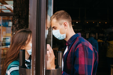 Man in medical protective face mask looking through window on her girl .Coronavirus pandemic
