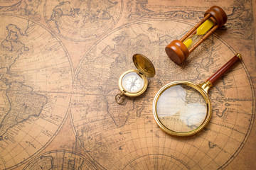 Old compass , magnifying glass and sand clock  on vintage map