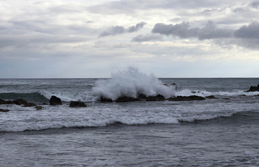 Storm clouds are approaching and with them a strong wind, which has brought a huge number of medium waves, which persistently crash the rocky cliffs. Dominance of the seas and ocean. Dangerous situati