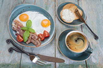 Fried eggs,  bacon, tomato, toast and a cup of coffee