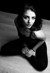 Black and white portrait of young woman sitting on a floor.