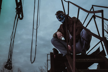 a young man in a factory during the Apocalypse in a castle and with a saw