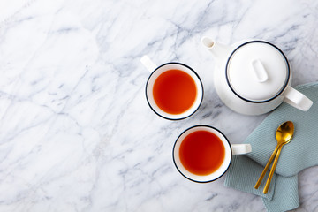Tea in mugs with teapot on marble background. Copy space. Top view.