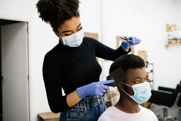 African-American hairdresser peeling an African-American man in a face mask