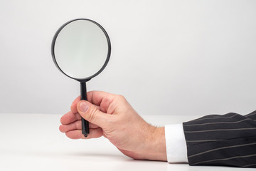 Hand of a man with a magnifying glass close-up. Magnifying glass