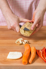 Close up of hands peeling and cutting celery root on a wooden board. Healthy food preparation concept