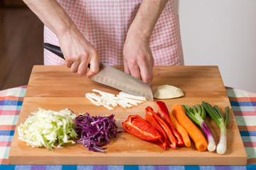 Close up of hands chopping celery root on a wooden board. Healthy food preparation concept