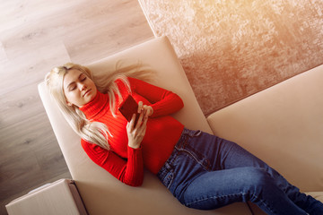 Sexy pretty young blonde woman in red lying on bed use of cellphone, looking at message, reading, waiting for call. Smiling attractive girl reading social networks news, take selfie, standing at home.