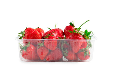 Heap of vivid saturated ripe red strawberries laying in big plastic transparent container and one big berry laying near the box isolated on clear white background