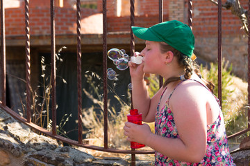 Portrait of Obese blonde teenager with braids in her hair making soap bubbles. Concept of children...