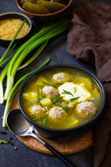 The concept of healthy and diet food. Russian or Ukrainian cuisine. Soup with meatballs, bulgur and pickled cucumbers on a dark stone table.