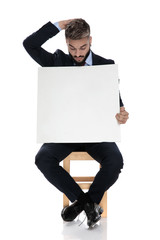 young businessman in suit holding empty board